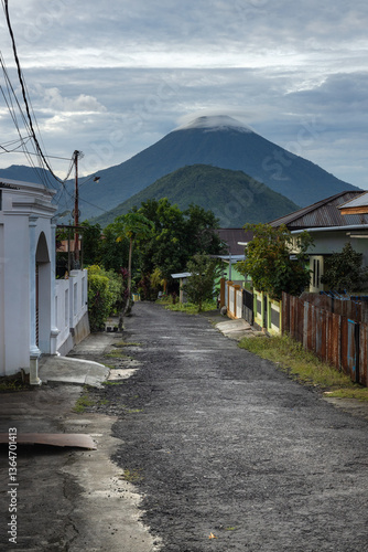 A narrow path down the street in the village of Ternate island with a view of a volcano on adjacent Tidore island in North Maluku province