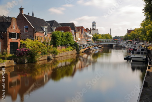 Reflections of traditional houses, barges and boats on the little canal (klein Diep) in Dokkum, Friesland, Netherlands, with the Oud Stadhuis (Old Town Hall, built in 1610) in the background