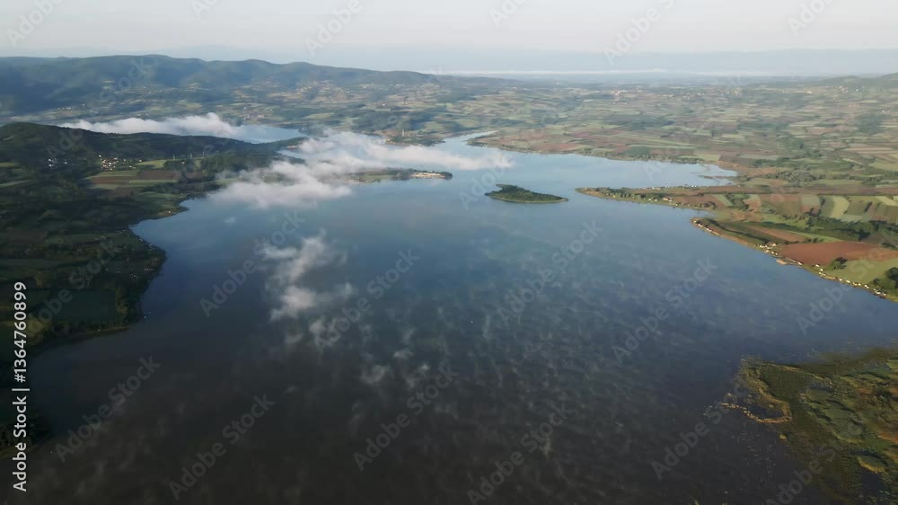 Stunning aerial view of a serene lake surrounded by lush landscapes in early morning light Stunning aerial view of a serene lake surrounded by lush landscapes in early morning light