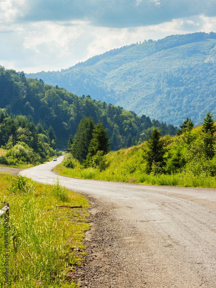 old country road winding through mountainous countryside. curvy pass direction to valleyy. wonderful summer landscape. spruce forest along the way. bright sunny weather. travel backcountry concept