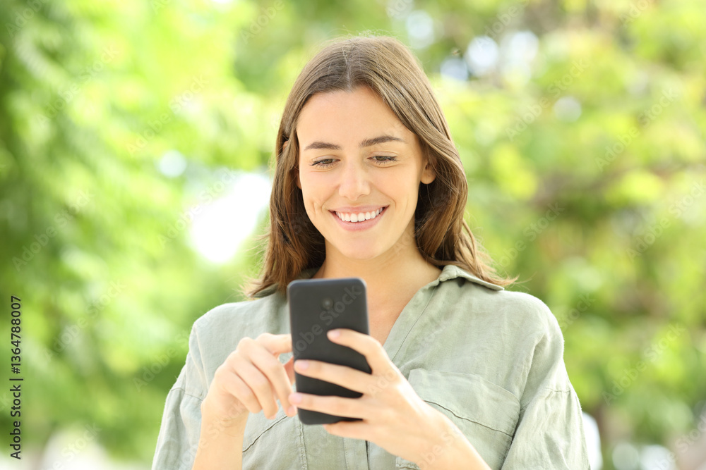 Woman walking using cell phone in a park Woman walking using cell phone in a park