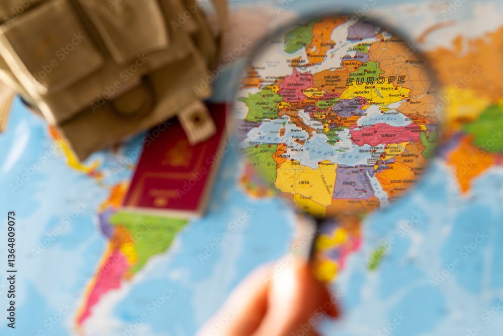 Top view of a Europe map with magnifying glass highlighting critical emergency zones alongside a survival backpack,and passport symbolizing crisis preparedness. Top view of a Europe map with magnifying glass highlighting critical emergency zones alongside a survival backpack,and passport symbolizing crisis preparedness.