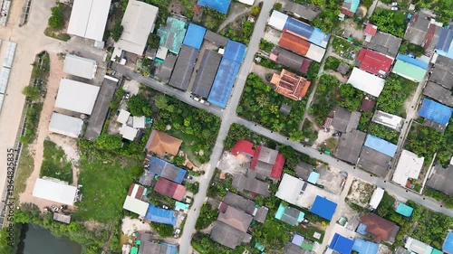 Aerial View of Residential Area with Colorful Roofs, Green Spaces, and Pond, Showcasing Vibrant Community and Tranquil Neighborhood with Diverse Houses and Intersecting Roads.