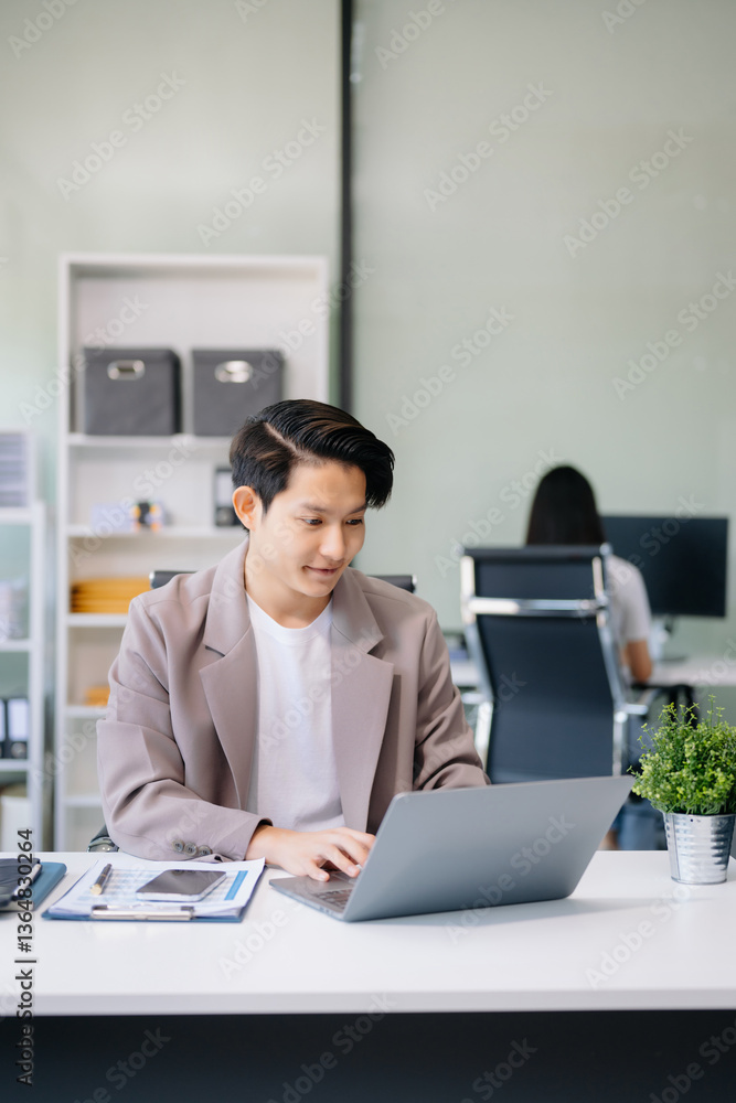 Young businessman working with laptop, tablet and taking notes on the paper at office.. Young businessman working with laptop, tablet and taking notes on the paper at office..