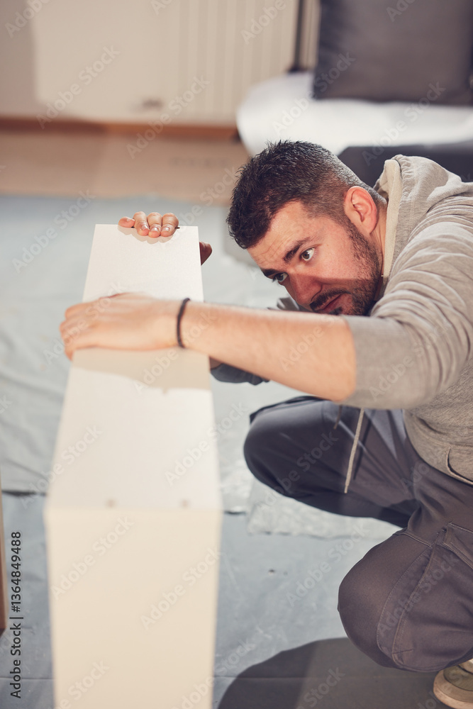 Man working and assembling furniture in a new apartment.