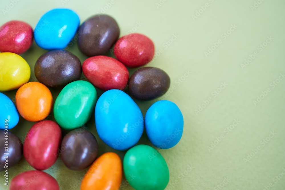 Colorful chocolate candies on green background. Selective focus. Colorful chocolate candies on green background. Selective focus.