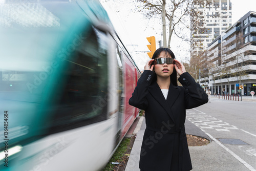 Asian businesswoman with cyberglasses watching speeding tram