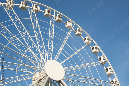 Obraz na płótnie Part of white Ferris wheel against blue sky on cloudless summer day. Outdoors. Amusement park. w salonie