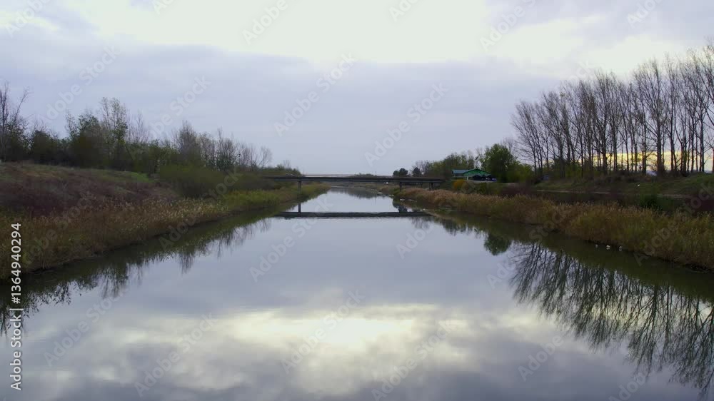 Calm waters reflect the sky at dawn near a quiet bridge surrounded by nature Calm waters reflect the sky at dawn near a quiet bridge surrounded by nature