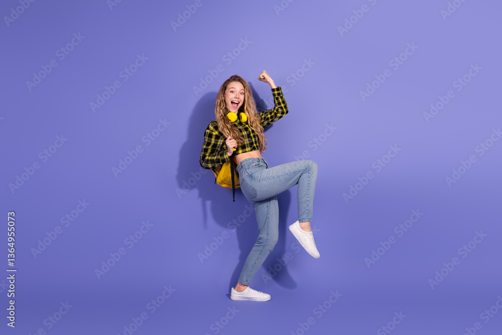 Obraz premium Young woman celebrating joyfully on purple background wearing trendy outfit