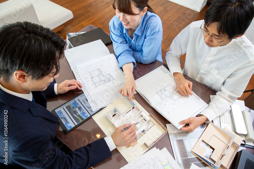Housing sales: Meeting with the client couple while looking at blueprints in a model room