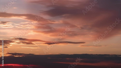 Day to night time lapse. The sun is setting down against the background of running dramatic clouds and painting them in bright fiery colors
