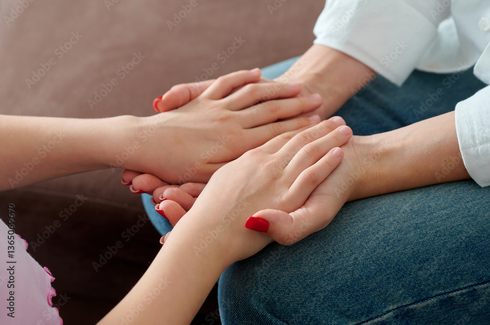 Fototapeta premium Two hands clasping gently, expressing comfort, on a soft couch. 