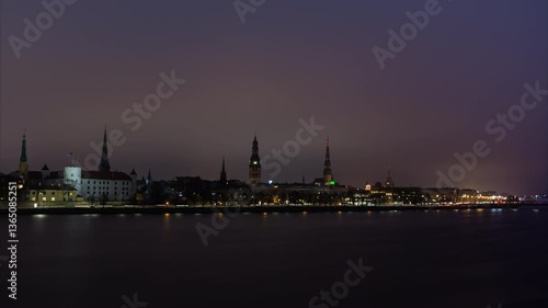 Time lapse. Night panoramic view of the historical center of Riga across the Daugava river. Beautiful embankment lighting and dense night traffic
