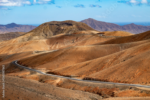 Winding road through arid hills of Fuerteventura's volcanic terrain.