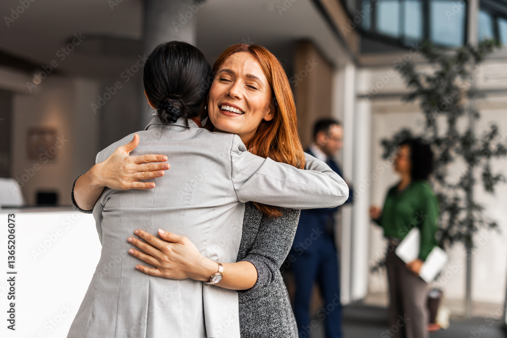 Two Professional Women Hugging in a Modern Office
