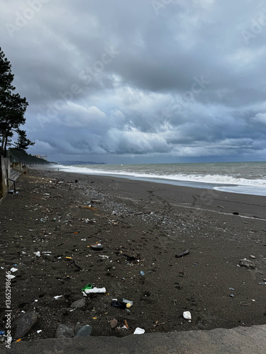Obraz na płótnie Polluted black sand beach with ocean waves under a stormy sky w salonie