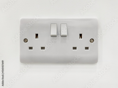 Standard British double plug socket with on-off switch. Electrical outlet on a white wall