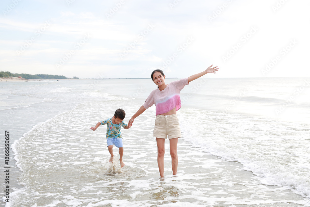 Cheerful Asian mother and little boy enjoy playing on tropical sand beach at sunrise. Happy family mom and son having fun in summer holiday. Cheerful Asian mother and little boy enjoy playing on tropical sand beach at sunrise. Happy family mom and son having fun in summer holiday.
