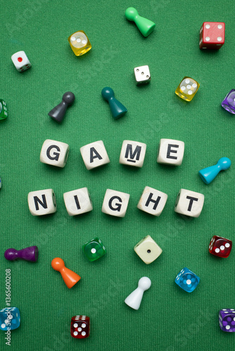 Fotografie Word dice showing the phrase 'Game Night' with a selection of colourful dice and game tokens lying around it on a vibrant green baize fabric