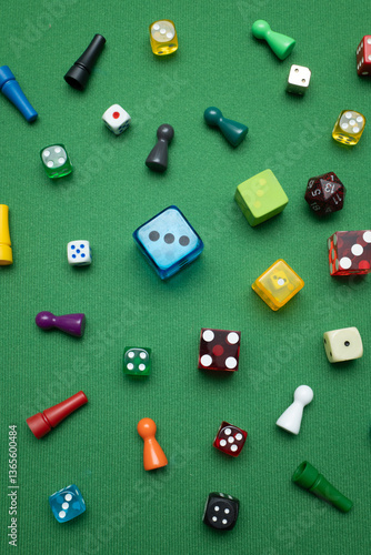 Fotografie Colorful dice and game tokens lying on a green baize cloth.