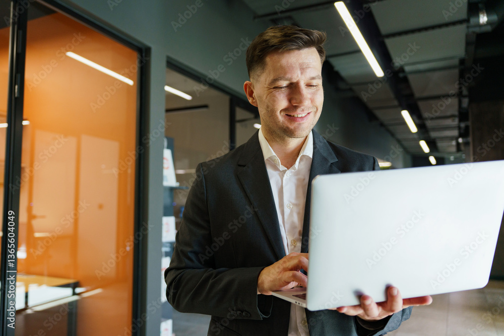 Business professional smiles while working on laptop in modern office environment during daytime Business professional smiles while working on laptop in modern office environment during daytime