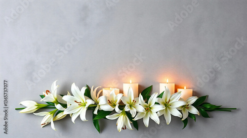 White lilies and burning candles on textured gray background