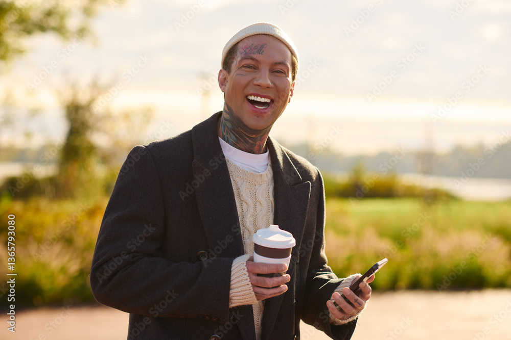 Stylish young man with tattoos enjoys coffee while posing in a sunny outdoor setting Stylish young man with tattoos enjoys coffee while posing in a sunny outdoor setting