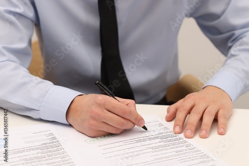 Obraz na płótnie Man signing licensing agreement document at white table indoors, closeup w salonie