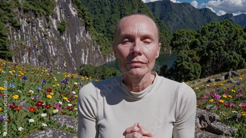 serene and pale middle-aged woman meditates and prays in the outdoors mountains, cinematic composition with beautiful light and flowers