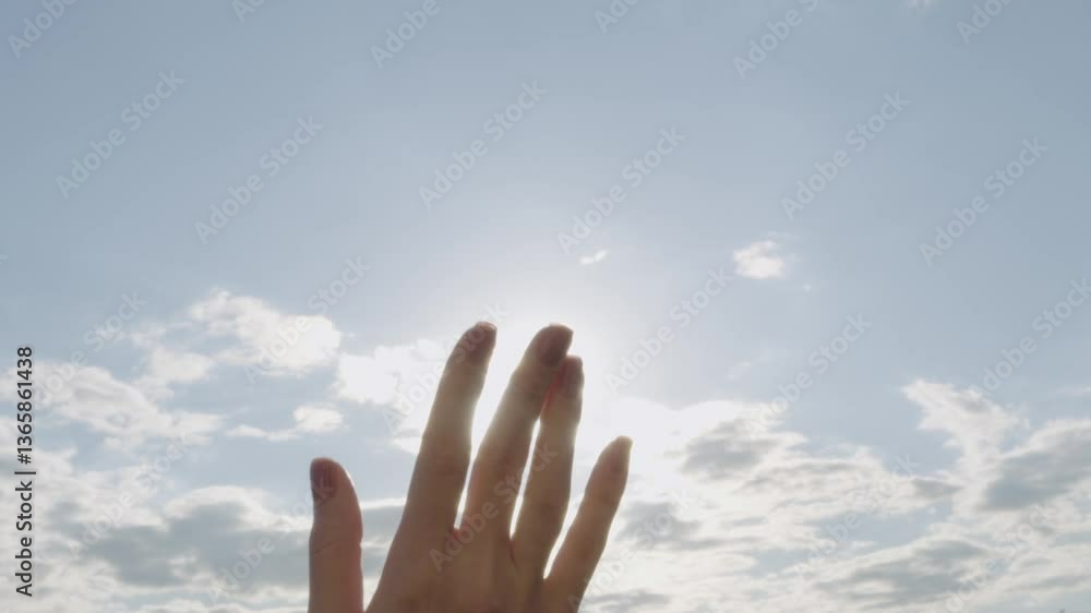 Hand reaching for sunlight in the sky