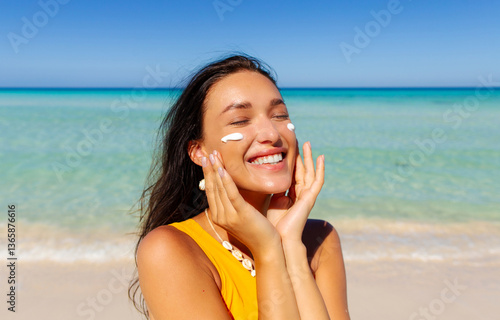 Photos Portrait of beautiful woman applying sun cream on face, standing on sandy beach with turquoise water on background