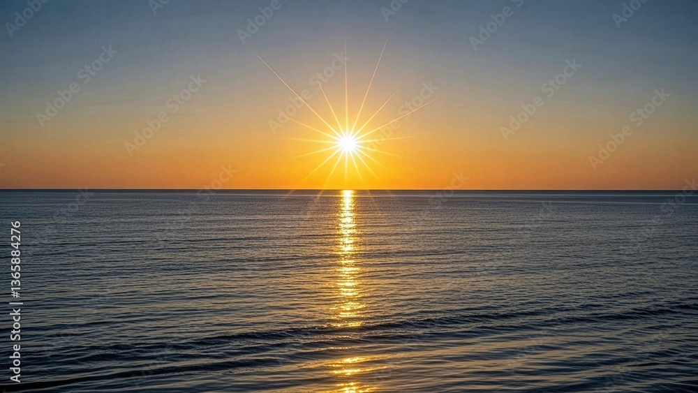 Obraz premium Golden rays of the rising sun creating a starburst effect on calm ocean waters, painting the sky with warm orange and yellow hues for a breathtaking natural view