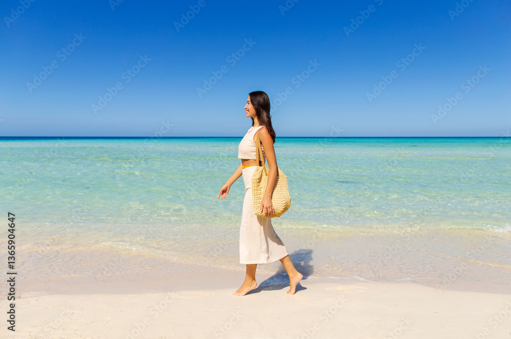 Side view of woman tourist with bag walking on tropical island, enjoying turquoise ocean water and sandy beach, full length shot Side view of woman tourist with bag walking on tropical island, enjoying turquoise ocean water and sandy beach, full length shot