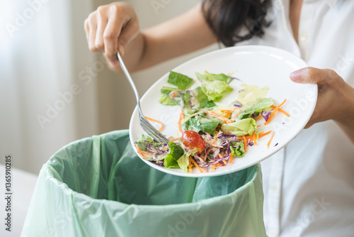 Billede på lærred Compost from leftover food asian young housekeeper woman, female hand holding salad bowl use fork scraping waste, rotten vegetable throwing away into garbage, trash or bin