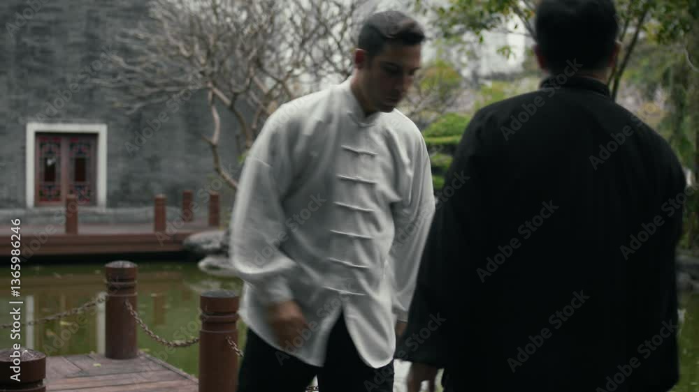 A kung fu master trains with a student in a garden setting, showing discipline A kung fu master trains with a student in a garden setting, showing discipline