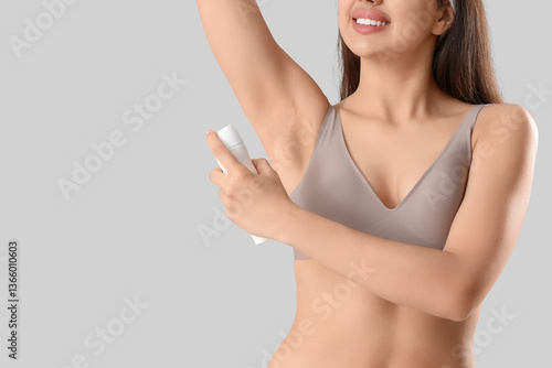 Young woman spraying deodor...
