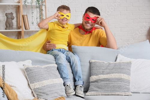 Little boy with his father in superhero costumes at home