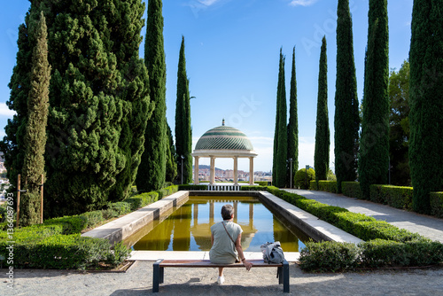 Woman sitting enjoying the views of a pond and a dome in Malaga
