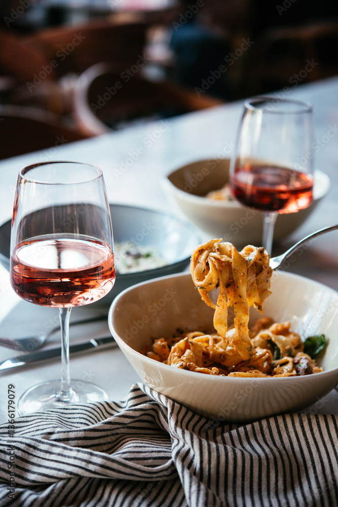 Having a pasta dinner with rose wine at home or in a restaurant.