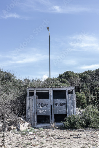 Obraz na plátně An abandoned wooden beach hut in Greece with a satirical message, set in a dry, overgrown landscape