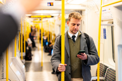 Obraz na płótnie Businessman using smartphone while standing on subway train w salonie