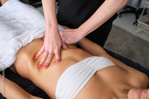 Obraz na płótnie Professional masseuse performing abdomen massage on young woman lying on massage table in spa salon w salonie