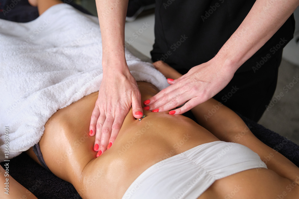 Masseuse massaging woman belly with red nail polish in a spa