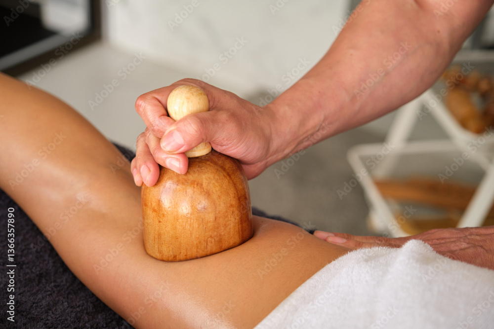 Therapist applying anticellulite massage on woman leg with wooden maderotherapy tool
