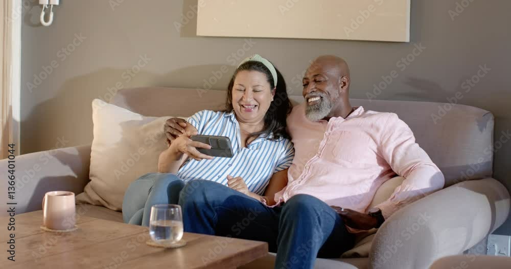 Senior diverse couple relaxing on sofa, enjoying video call on smartphone at home Senior diverse couple relaxing on sofa, enjoying video call on smartphone at home