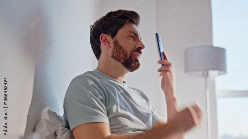 Fototapeta premium Relaxed brunette talking mobile phone in cozy bed apartment closeup. Man calling