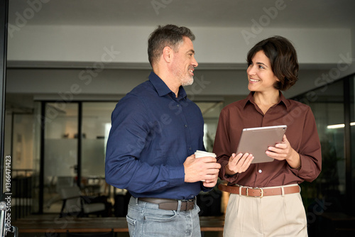 Obraz na plátne Two happy hispanic professional business man and woman having friendly conversation at work