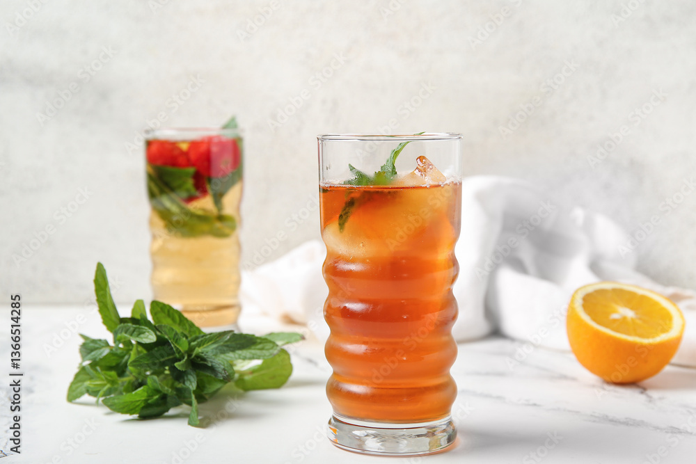 Fototapeta premium Glasses of ice tea with orange and strawberry on white background