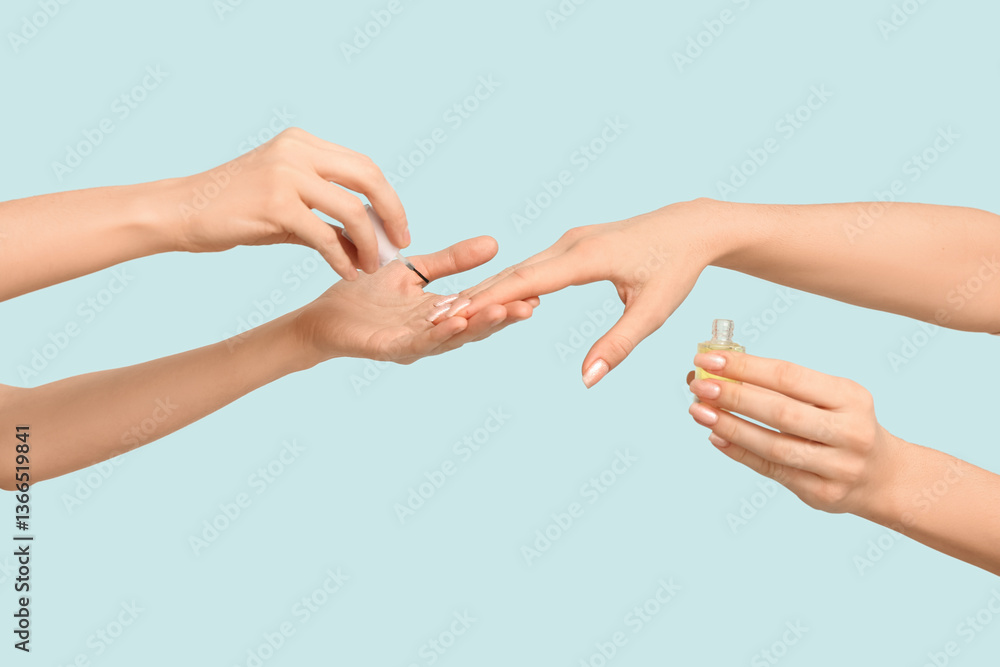 Female hands with bottle of cuticle oil on blue background Female hands with bottle of cuticle oil on blue background